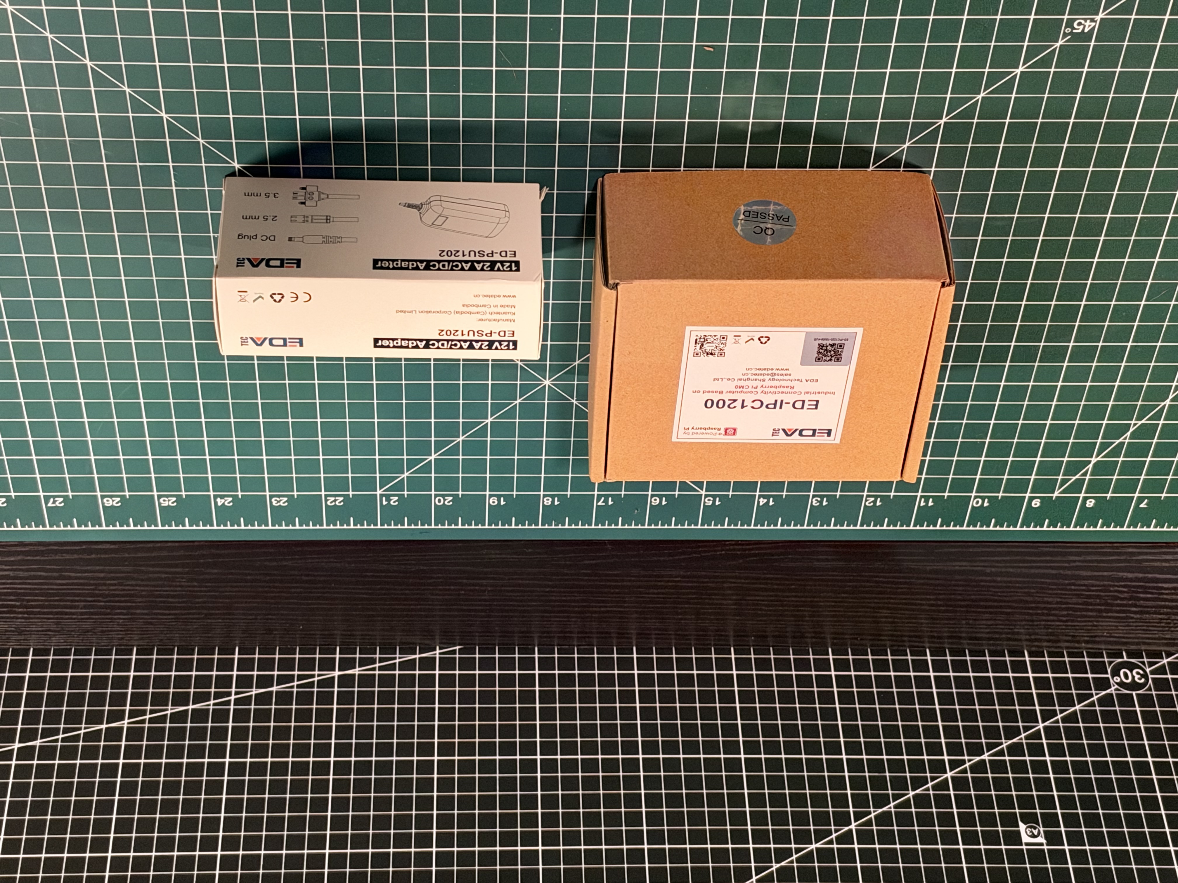 Closed EDATEC ED-IPC1200-family product box beside the included AC to DC power adapter box