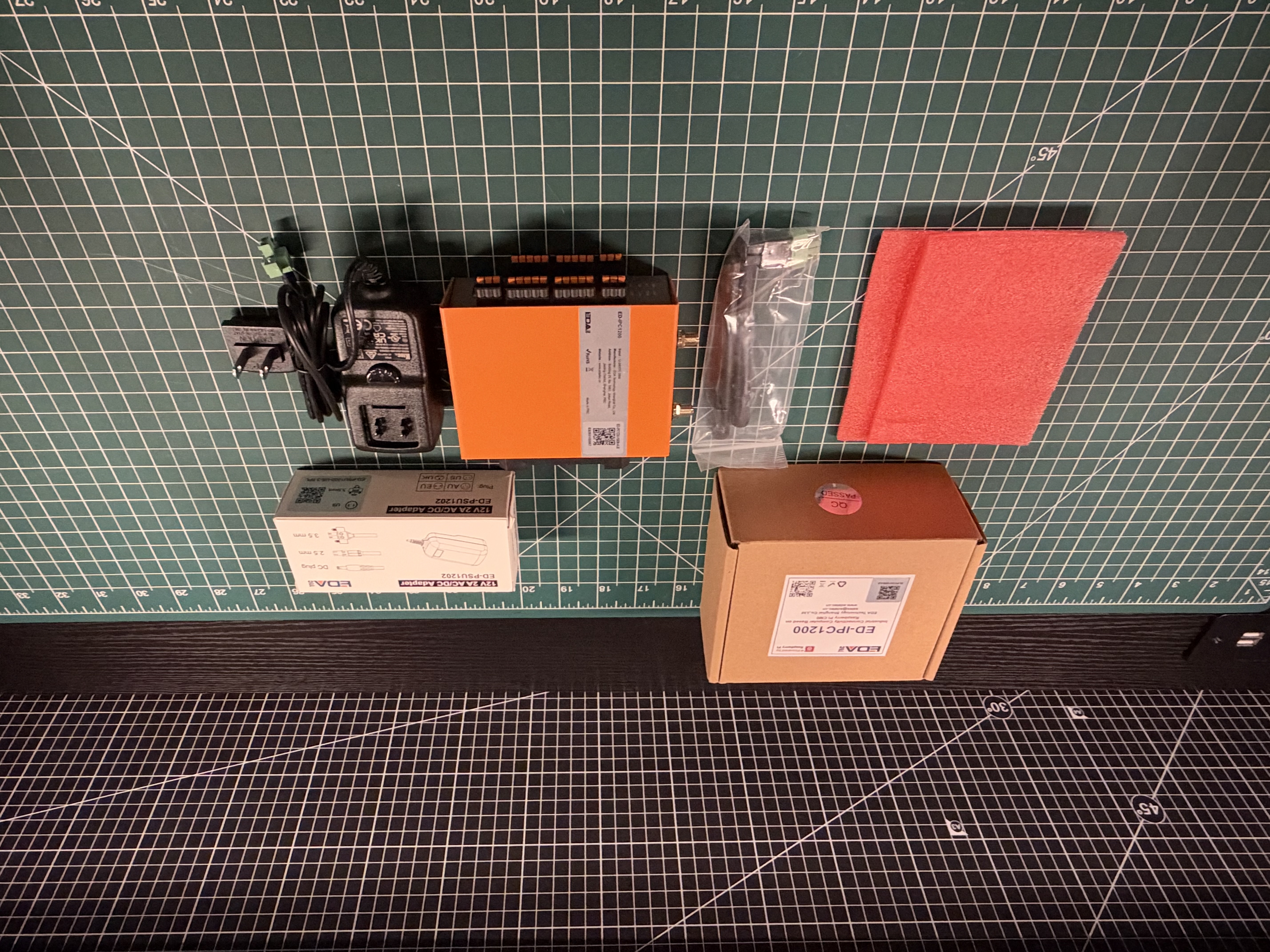 EDATEC ED-IPC1220 industrial computer, power supply, antennas, connectors, and packaging laid out on a cutting mat
