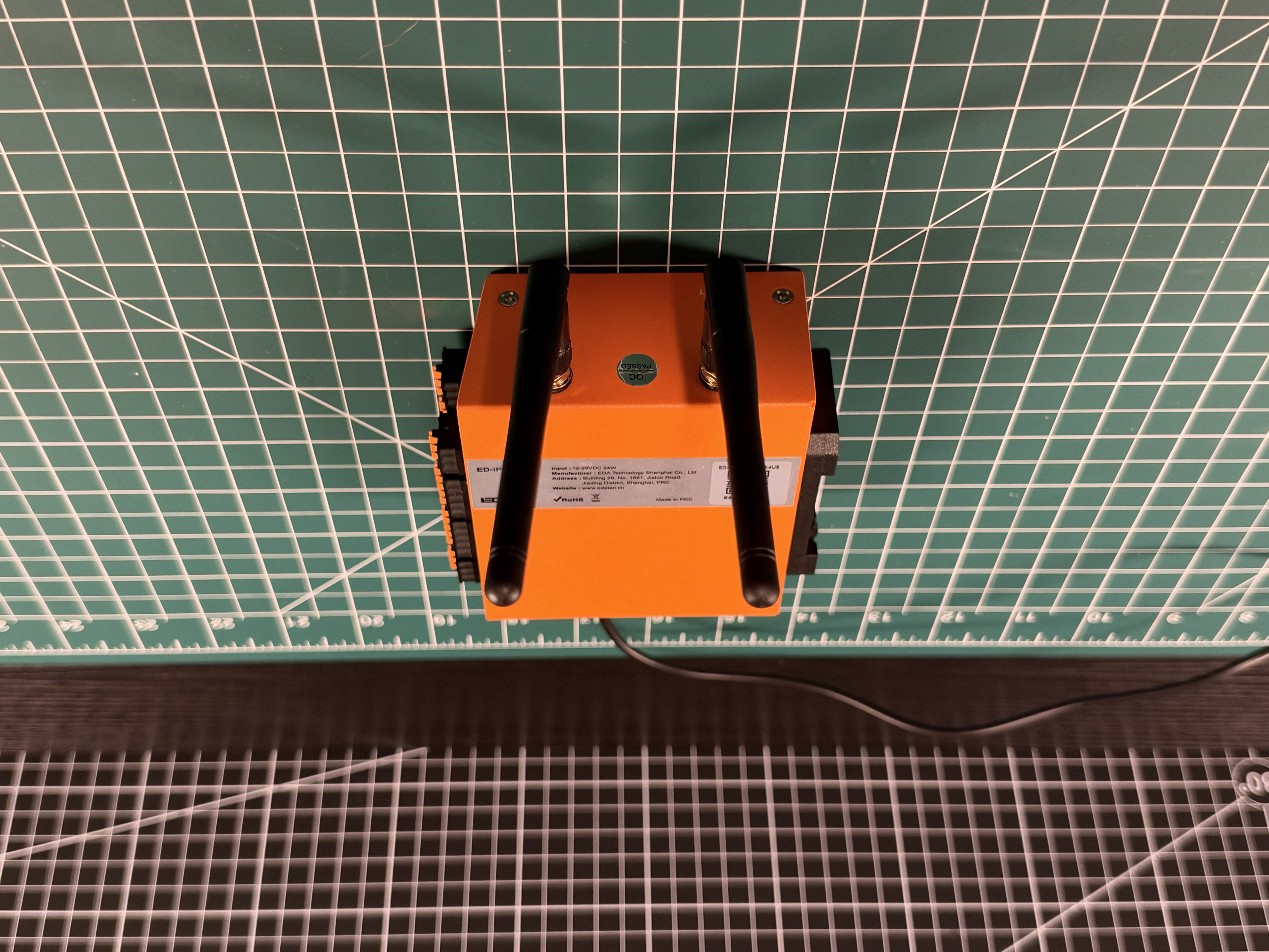 Rear three-quarter view of the orange ED-IPC1220 enclosure with two antennas attached