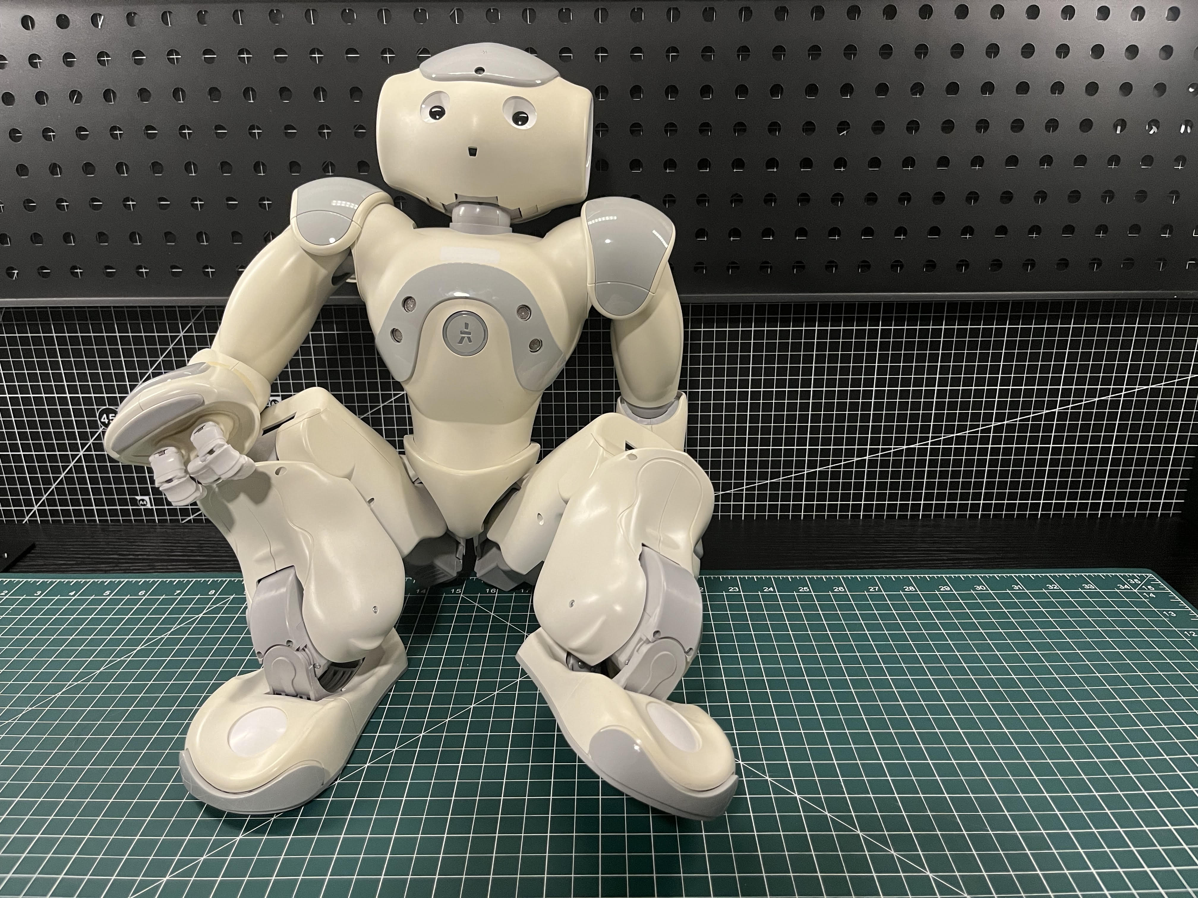 First-generation Aldebaran NAO humanoid robot seated on a workbench